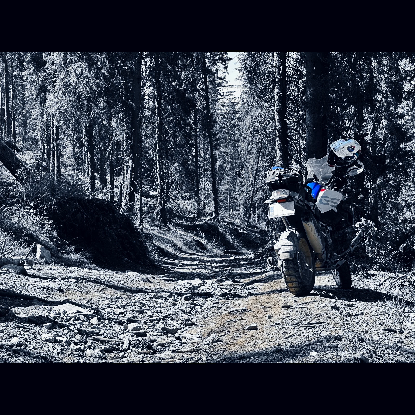Motocicleta parcată pe o cărare stâncoasă, în pădure